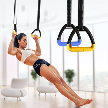 A person exercising with a yellow and blue suspension training ring equipment in a bright indoor space.